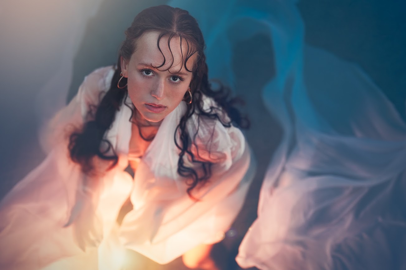 Woman wrapped in flowing fabric lit by a warm glow